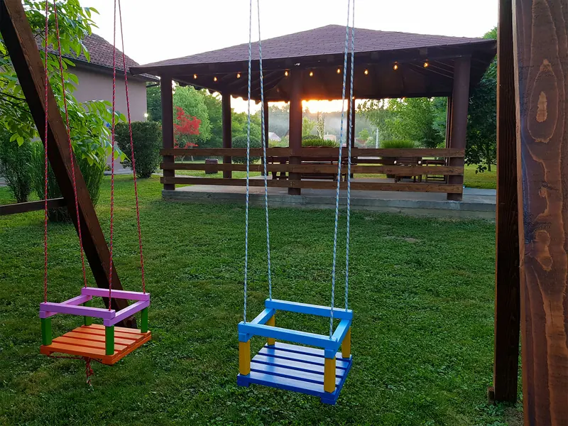 Ljuljačke ispod pokrivene terase s viseća svjetlima